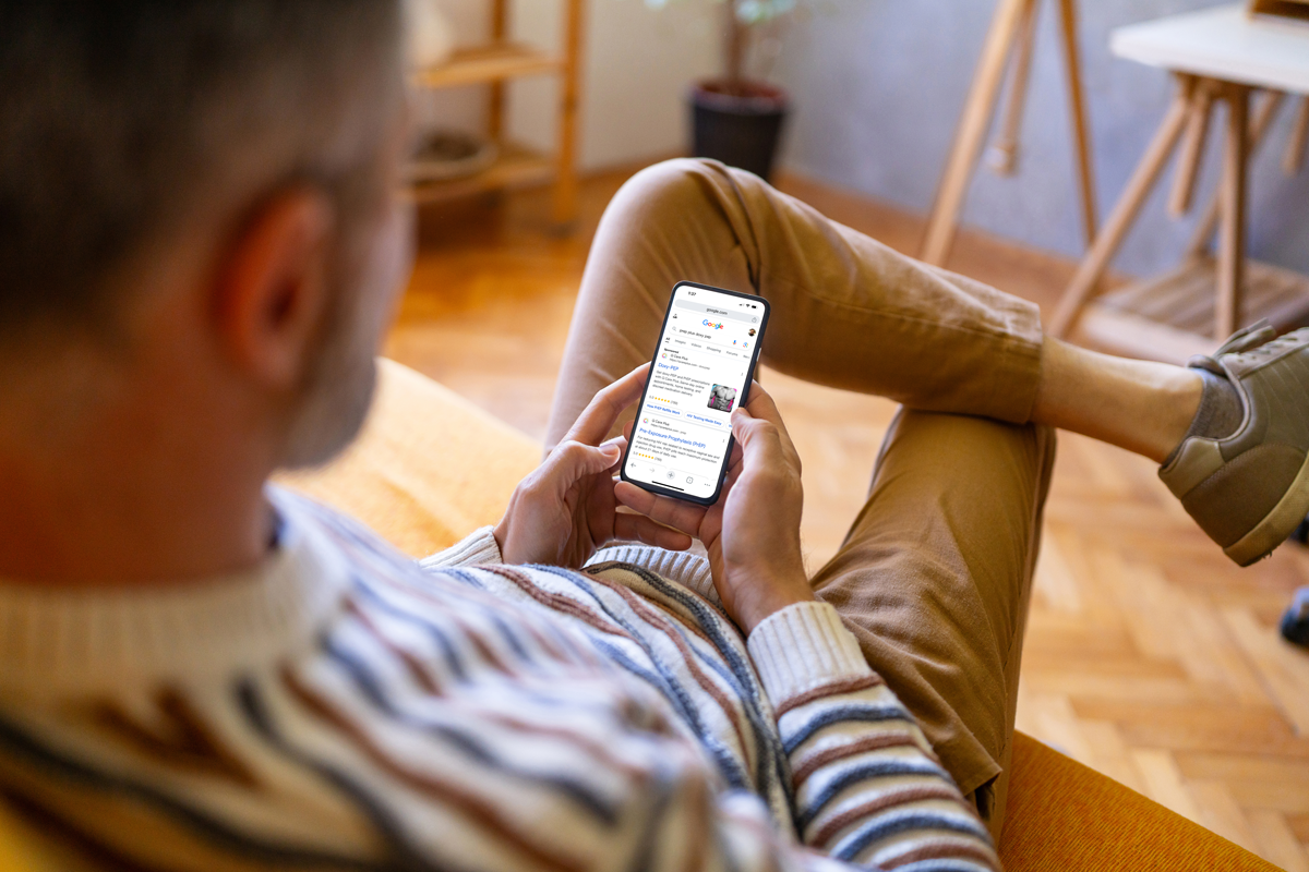 Person scrolling through Google search results on a mobile device, highlighting a Q Care Plus PrEP ad.